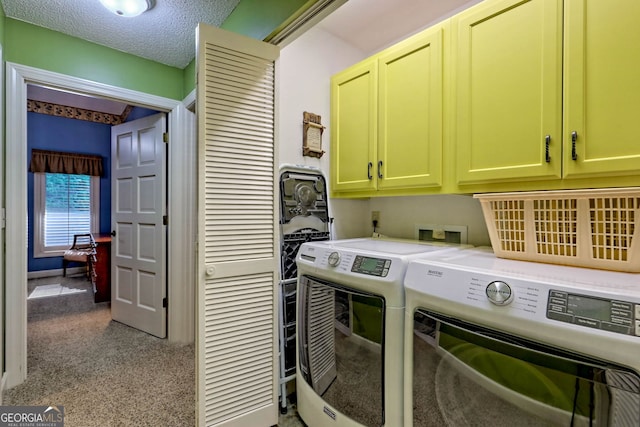 laundry area featuring cabinets, a textured ceiling, and washing machine and clothes dryer