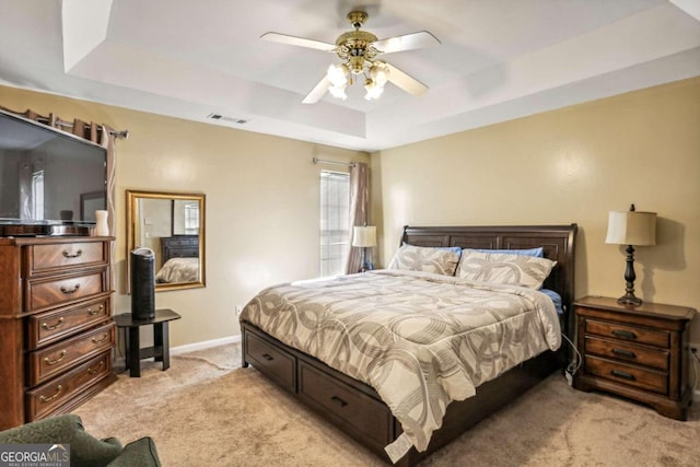 carpeted bedroom featuring ceiling fan and a raised ceiling