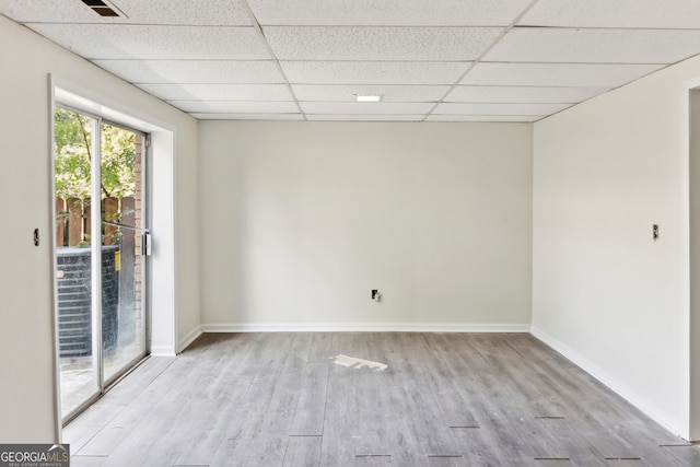 spare room featuring a paneled ceiling and light wood-type flooring