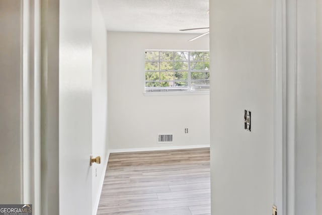 spare room featuring a textured ceiling, light wood-type flooring, and ceiling fan