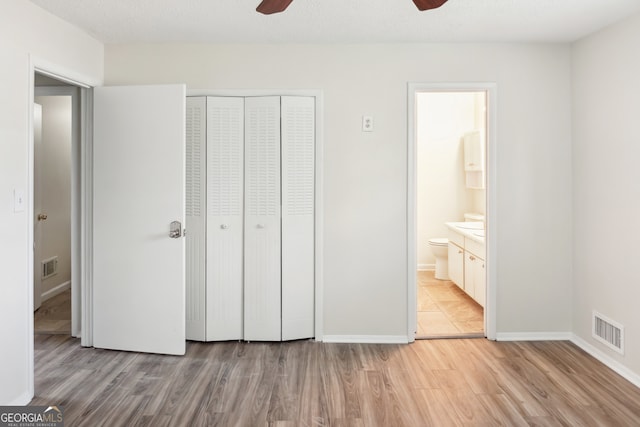 unfurnished bedroom with light hardwood / wood-style flooring, ensuite bathroom, a closet, and ceiling fan