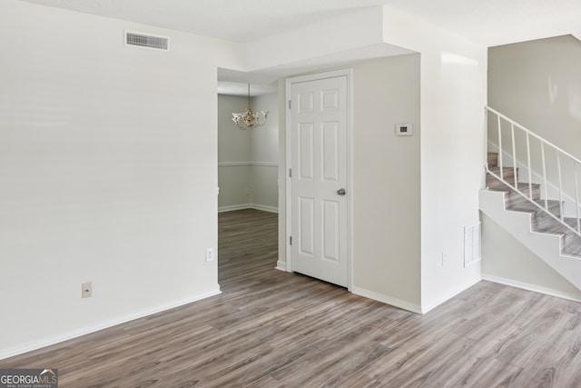 unfurnished room with a chandelier and wood-type flooring