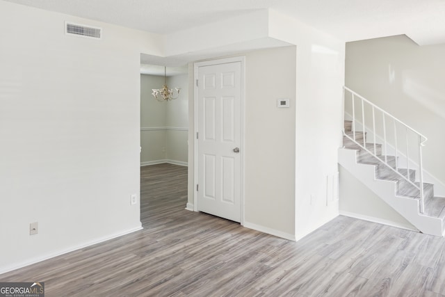 empty room with a notable chandelier and light hardwood / wood-style flooring