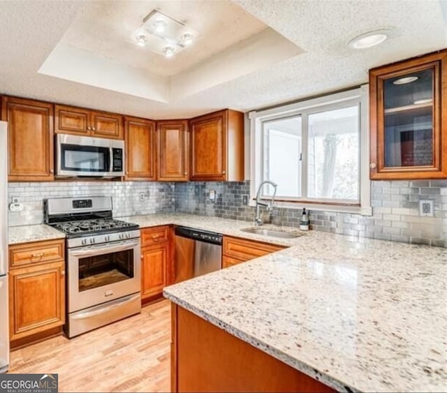 kitchen featuring appliances with stainless steel finishes, light stone counters, a textured ceiling, and a raised ceiling