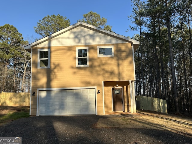 view of front facade with an attached garage, driveway, and fence