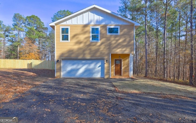 view of front of home with a garage, board and batten siding, driveway, and fence