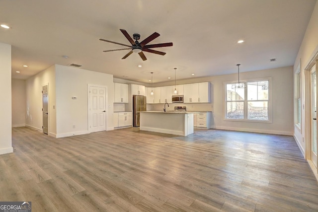 unfurnished living room with light wood finished floors, recessed lighting, visible vents, a ceiling fan, and baseboards