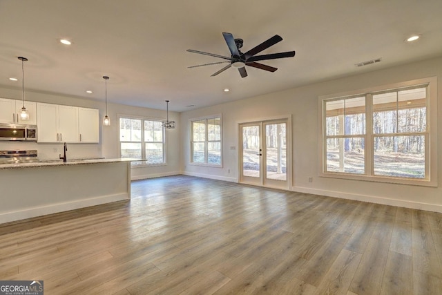 unfurnished living room featuring baseboards, ceiling fan, wood finished floors, french doors, and recessed lighting