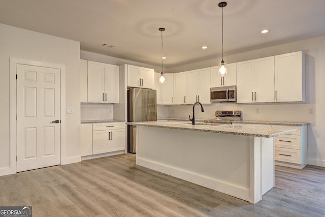 kitchen featuring stainless steel appliances, white cabinets, and an island with sink