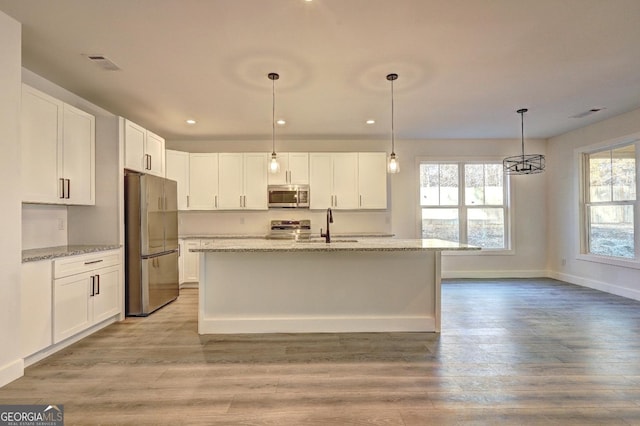 kitchen featuring light stone countertops, white cabinetry, stainless steel appliances, and decorative light fixtures