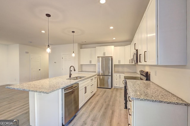 kitchen with white cabinets, a kitchen island with sink, stainless steel appliances, pendant lighting, and a sink