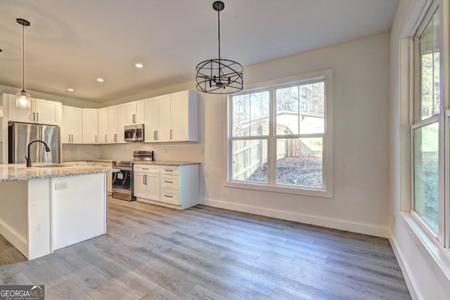 kitchen with appliances with stainless steel finishes, white cabinets, and light stone countertops