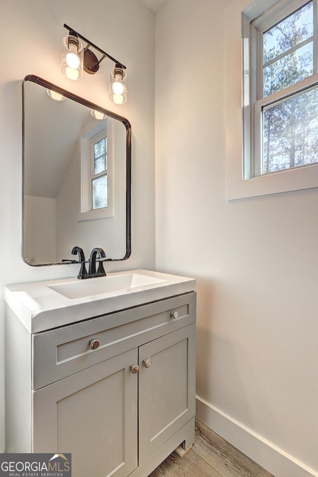 bathroom with wood finished floors, vanity, and baseboards