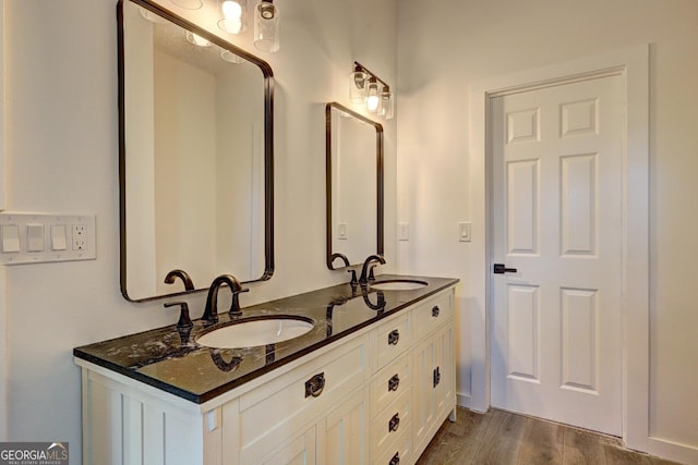 bathroom with double vanity, a sink, and wood finished floors