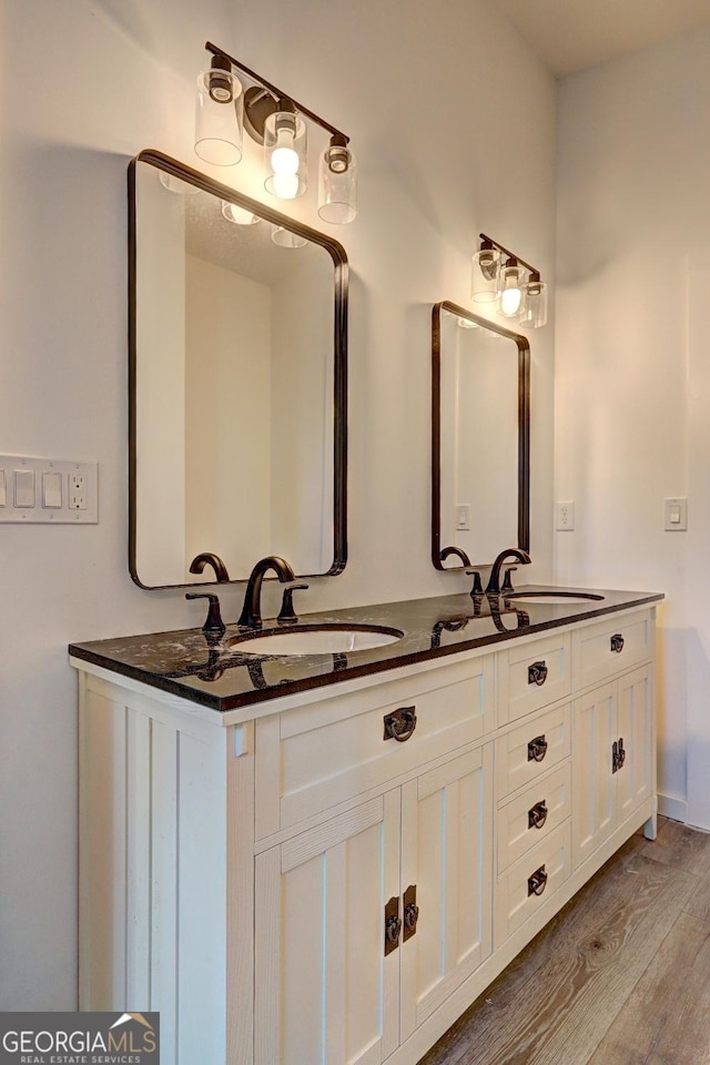 full bathroom with double vanity, a sink, and wood finished floors