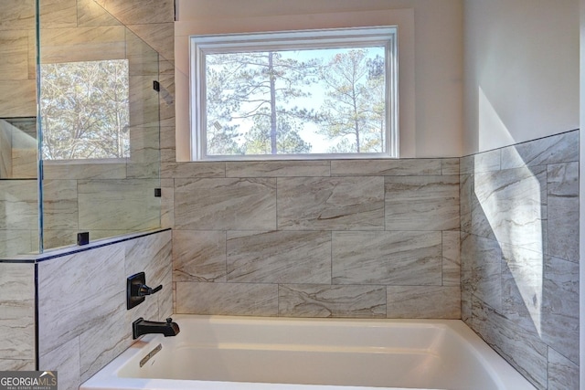 bathroom with a tub to relax in and tiled shower