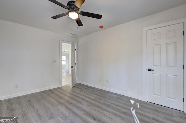 unfurnished bedroom featuring ceiling fan, light wood-style flooring, and baseboards