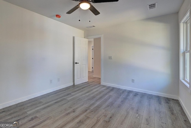 spare room with ceiling fan, light wood-type flooring, visible vents, and baseboards