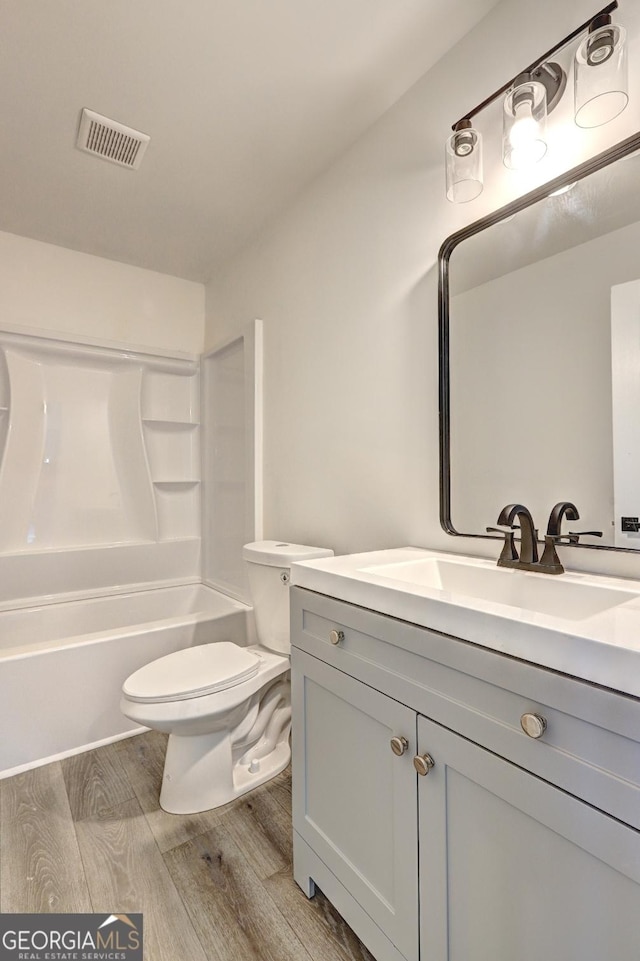 full bathroom featuring visible vents, toilet, wood finished floors,  shower combination, and vanity