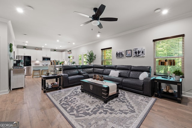 living room with ceiling fan, plenty of natural light, light wood-type flooring, and crown molding