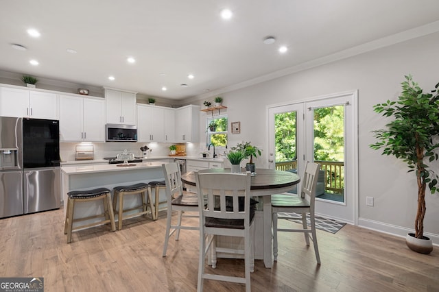 dining space with light hardwood / wood-style flooring, crown molding, and sink