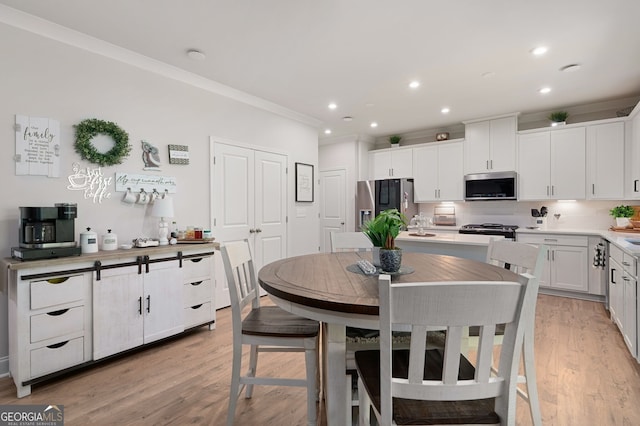 kitchen featuring decorative backsplash, ornamental molding, stainless steel appliances, light hardwood / wood-style floors, and white cabinetry