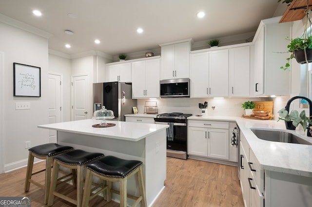 kitchen featuring a center island, sink, stainless steel appliances, light hardwood / wood-style flooring, and white cabinets