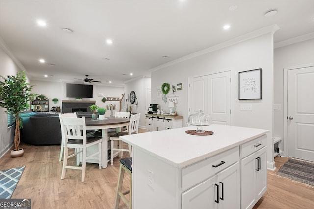 kitchen featuring light hardwood / wood-style floors, ceiling fan, a kitchen island, and white cabinetry