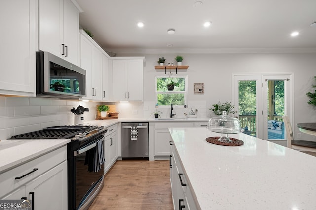 kitchen featuring white cabinetry, sink, light stone countertops, decorative backsplash, and appliances with stainless steel finishes