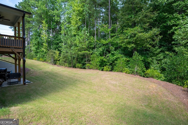 view of yard with ceiling fan and a wooden deck