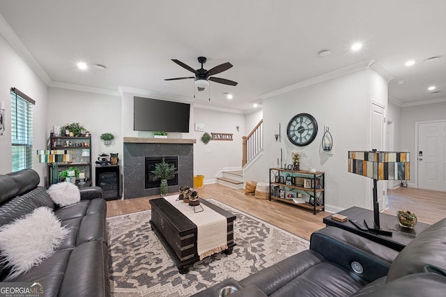 living room featuring a premium fireplace, crown molding, ceiling fan, and wood-type flooring