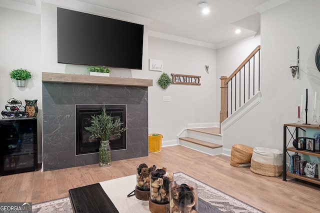 living room featuring a fireplace, wood-type flooring, and ornamental molding