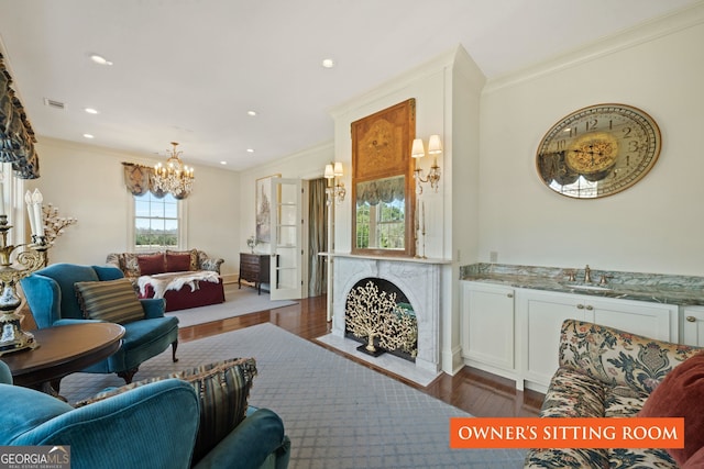 living room featuring sink, dark wood-type flooring, a notable chandelier, and ornamental molding