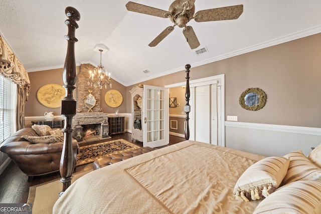 bedroom with hardwood / wood-style flooring, a stone fireplace, crown molding, and vaulted ceiling