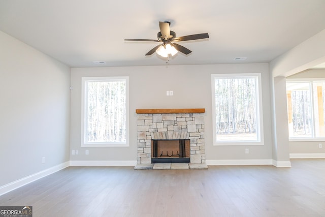 unfurnished living room featuring ceiling fan, a healthy amount of sunlight, a fireplace, and light hardwood / wood-style flooring