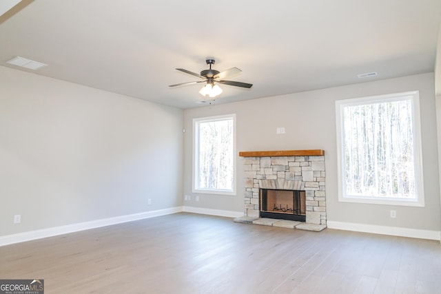 unfurnished living room with ceiling fan, a fireplace, and light wood-type flooring