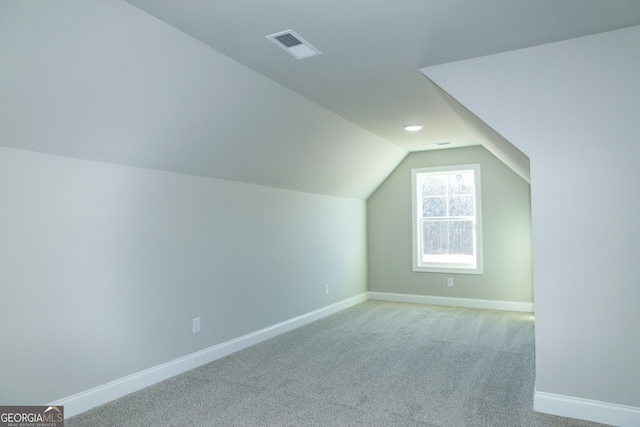 additional living space featuring light colored carpet and vaulted ceiling