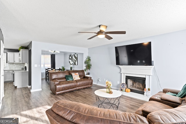 living room featuring ceiling fan, hardwood / wood-style flooring, and a textured ceiling