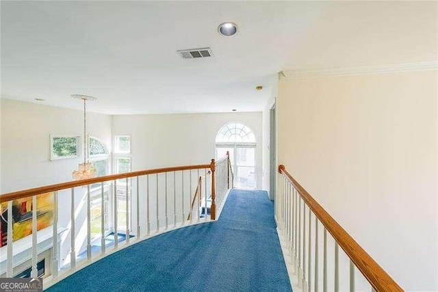 hall featuring a notable chandelier, ornamental molding, a healthy amount of sunlight, and carpet flooring