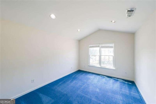 spare room featuring vaulted ceiling and dark colored carpet