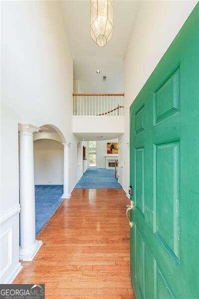 foyer entrance with an inviting chandelier, a high ceiling, ornate columns, and light hardwood / wood-style floors