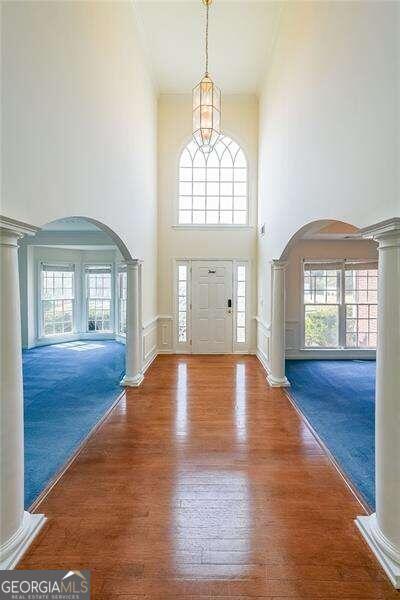 entrance foyer with decorative columns, carpet floors, and a towering ceiling