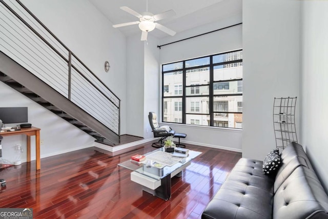 living room featuring ceiling fan, a high ceiling, and dark hardwood / wood-style floors