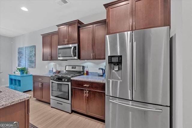 kitchen with appliances with stainless steel finishes, light hardwood / wood-style flooring, dark brown cabinetry, and light stone countertops