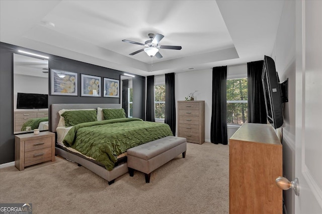 carpeted bedroom with a tray ceiling and ceiling fan