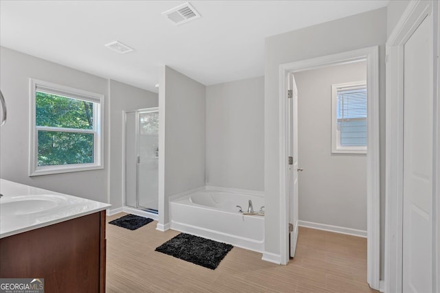 bathroom with vanity, hardwood / wood-style flooring, and plus walk in shower