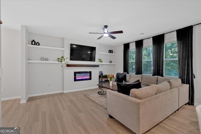 living room featuring built in shelves, light hardwood / wood-style floors, and ceiling fan