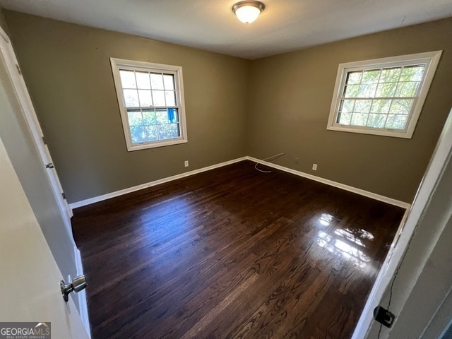 unfurnished room with dark wood-type flooring