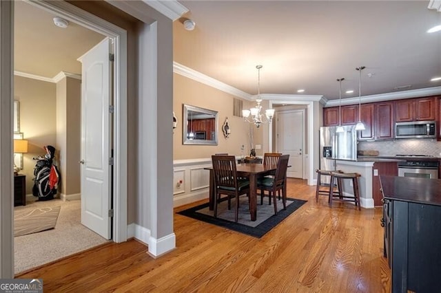 dining space featuring an inviting chandelier, ornamental molding, and light wood-type flooring