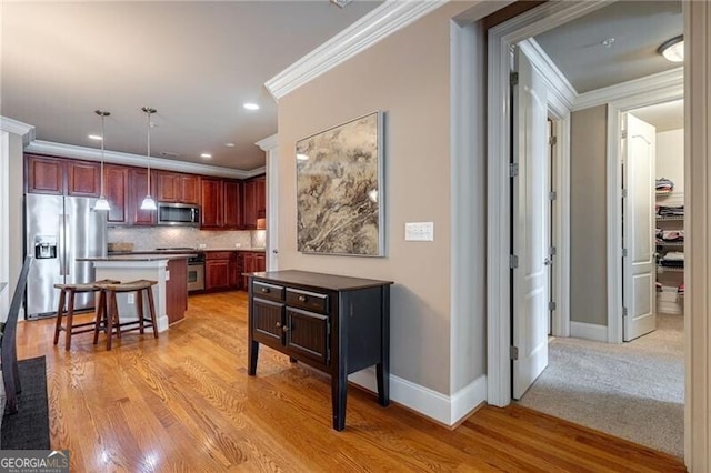 kitchen featuring decorative backsplash, a breakfast bar area, light hardwood / wood-style flooring, hanging light fixtures, and appliances with stainless steel finishes